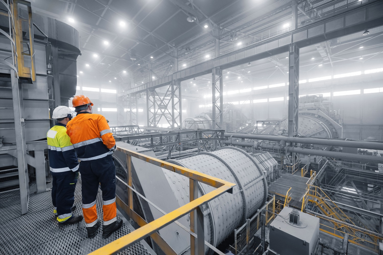 Two process engineers overlooking grinding mills in a mineral processing plant